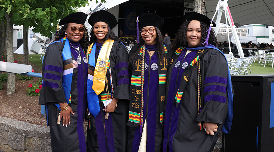 Four Suffolk Law graduates in their tams and gowns ahead of 2025 Suffolk University Law Commencement