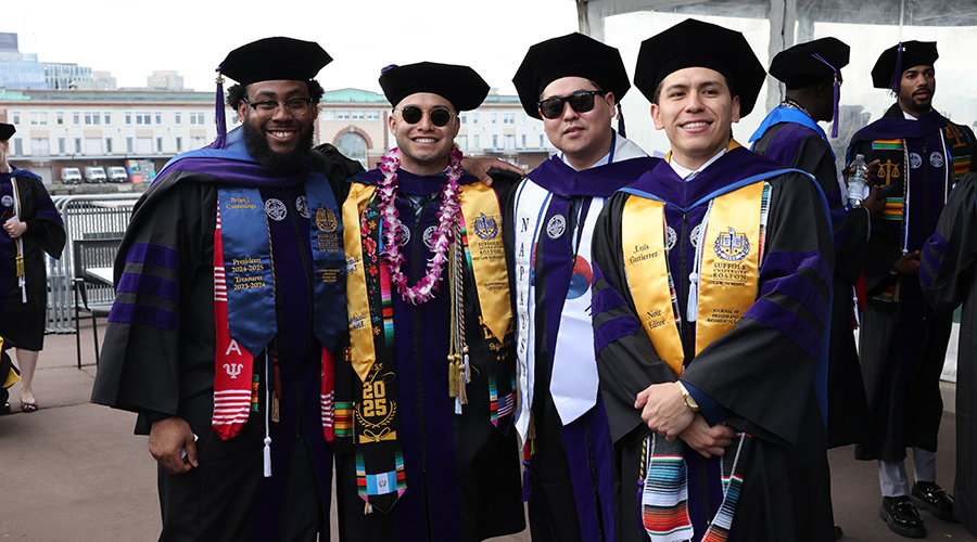 Four graduates in their tams and gowns with yellow stoles at the 2025 Suffolk Law Commencement