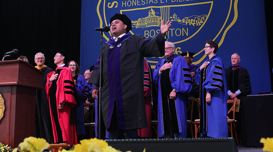 Nicholas Antonellis on the stage of the 2025 Suffolk Law School Commencement singing the National Anthem