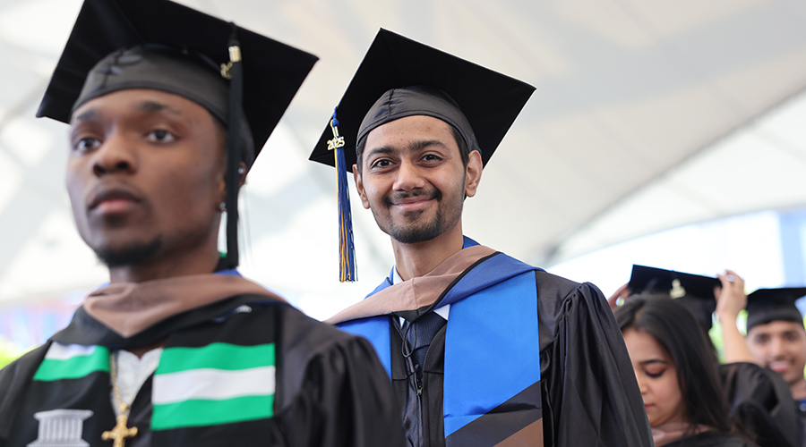 Students in academic regalia process into Commencement 2025