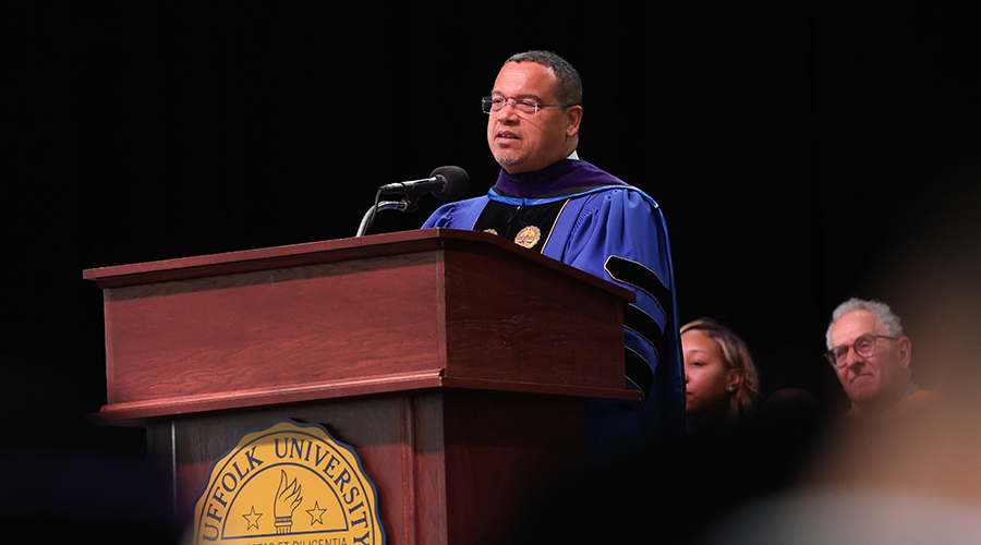 A man named Keith Ellison speaking from the podium at the 2025 Suffolk Law School Commencement