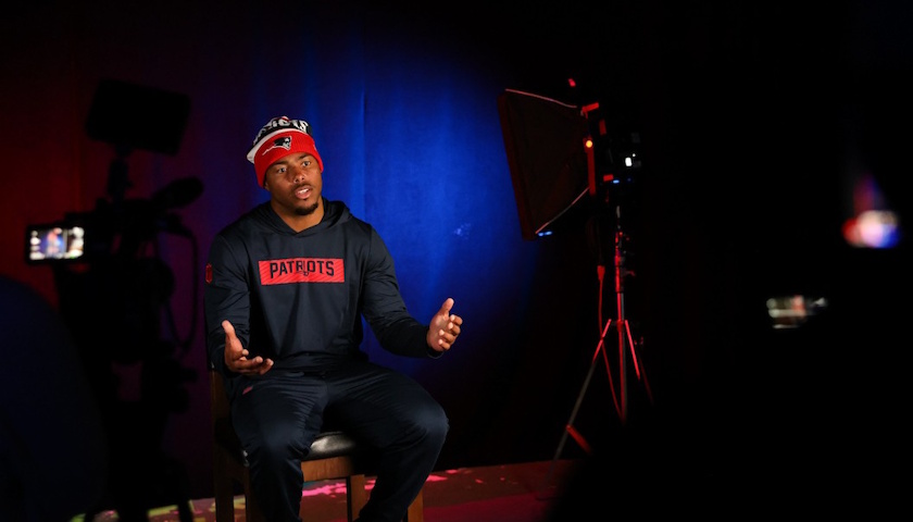 Patriots' player Marcus Jones being filmed in studio wearing a Patriots winter hat