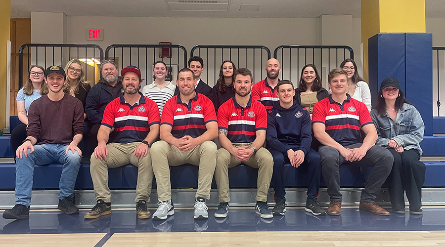 Members of the New England Free Jacks sitting on the bleachers at the media day on the Suffolk campus