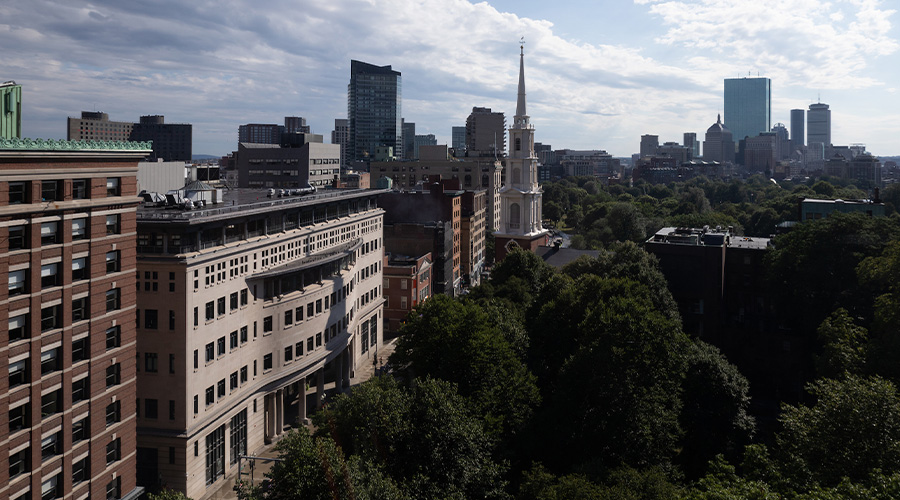 On the left, view of building along Tremont St with the Park St. Church tower in the middle; on the right the green trees of the Granary Burying Ground