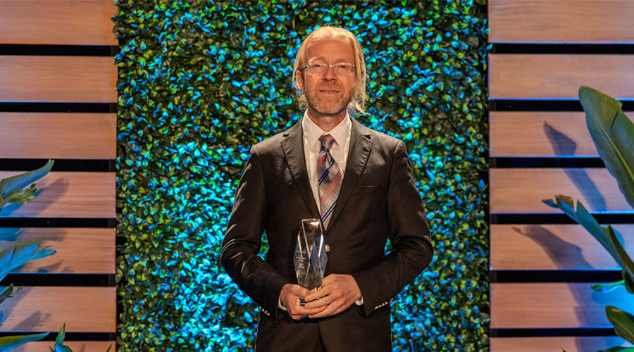 Professor Hasan Arslan holding the Eduventures award on a colorful stage