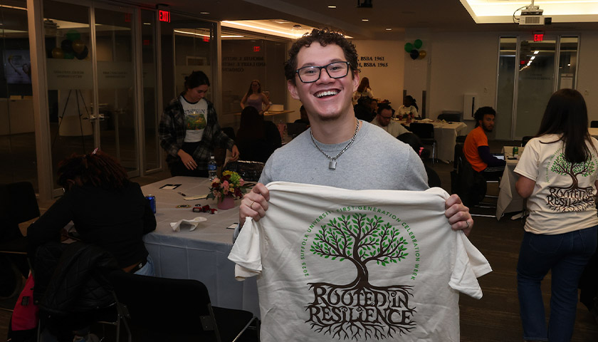 McNair Scholar David Rivera holds up a “Rooted in Resilience” t-shirt during First-Gen Week 2025