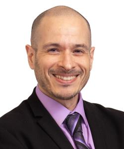 Headshot of Chris Paglia wearing a purple shirt and tie with jacket