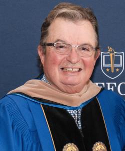 Kevin Donahue smiles in academic regalia at Commencement