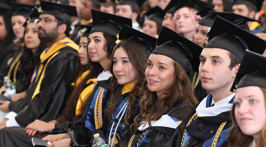 Graduating Suffolk students are seated and listening to Commencement ceremony speeches