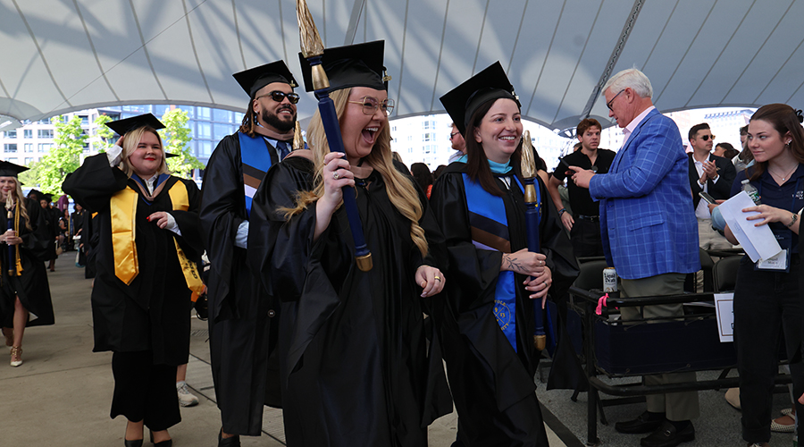 Smiling graduates march into the SBS Commencement ceremony