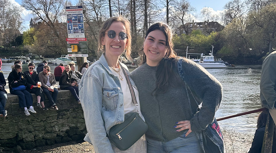 A professor and a student standing at a pub with the Thames River behind them