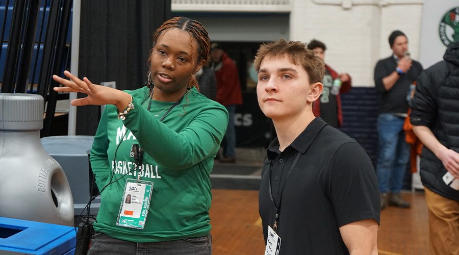 A Suffolk student (on the right) talks with a development coordinator at the Maine Celtics, who's pointing out something to him off camera