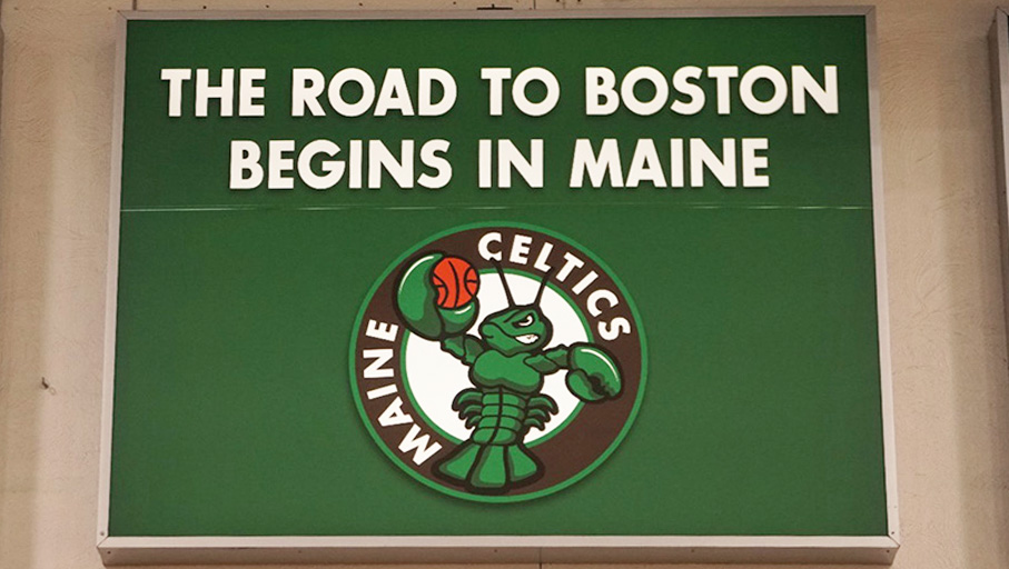 Green sign saying "The Road to Boston Begins in Maine" with the Maine Celtics logo below
