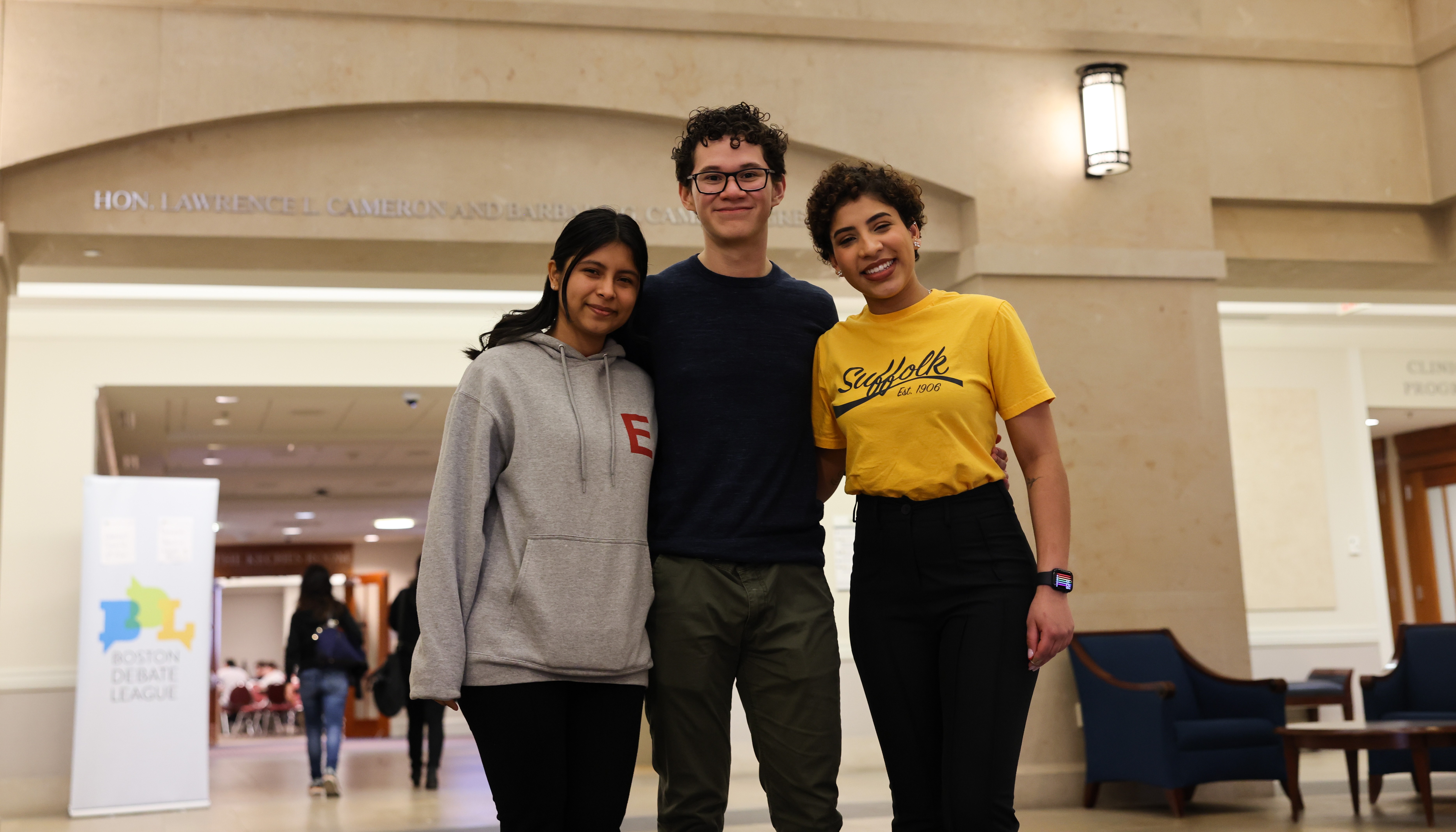 David Rivera stands in the lobby of Sargent Hall with two friends on debate tournament weekend