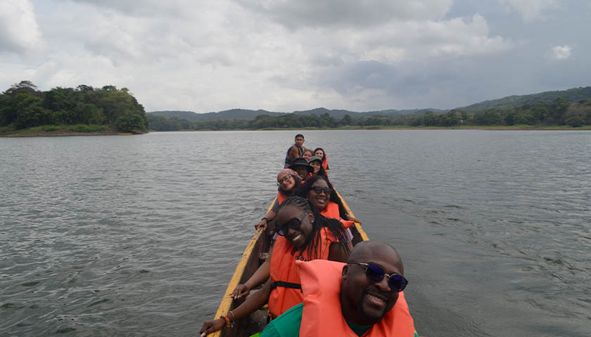 Suffolk students and their guide sitting in a long, narrow canoe in the Chagres River in Panama