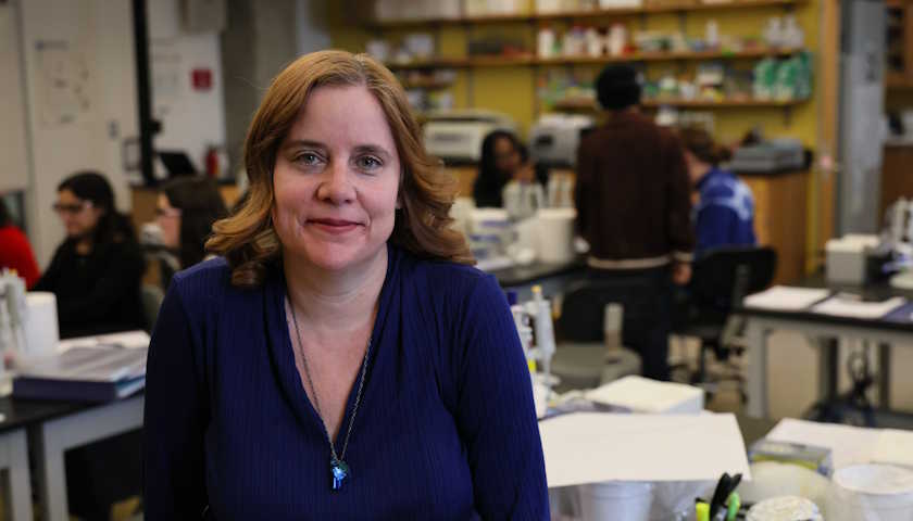 Professor Melanie Berkmen in a lab with students in the background