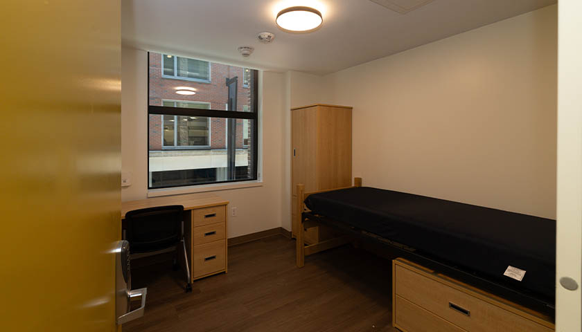 A 101 Tremont dorm room showing a desk, bureau, and bed