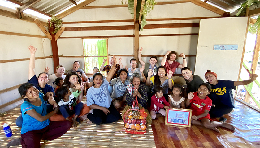 Cambodian family and students waving inside large room