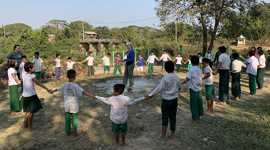 Children hand-in-hand form circle around Suffolk student in Myanmar