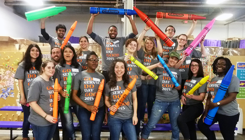 Students in Service Day T-shirts wave larger-than-life-size crayons