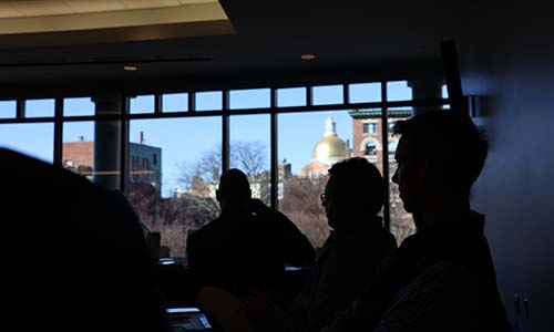 A view of the Boston Statehouse dome with silhouettes of event attendees in the foreground. 