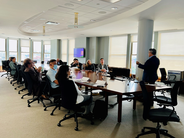 Participants at a Center for Innovation and Change Leadership event seated around an oval table listening to the speaker, Dr. Charles Noble.