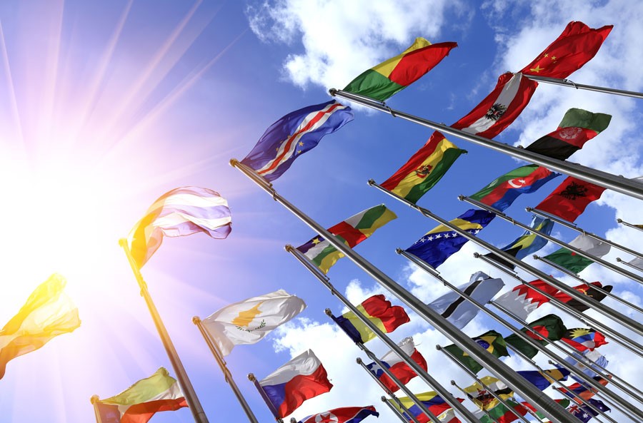 A stock photo taken looking up and many world flags with a bright sun streaming down.