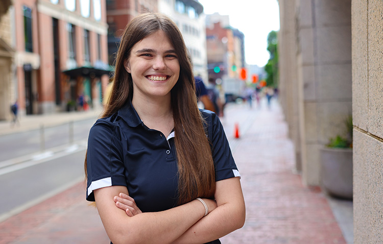 Suffolk honors student Anja Wight, Class of '27 Management/Marketing (Sports Marketing Concentration) Major, stands confidently in front of the entrance to 73 Tremont street on campus.
