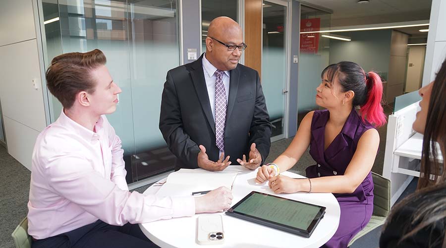 Two graduate students in discussion with a professor