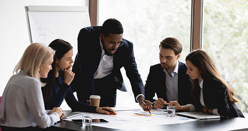 Group of people in business attire all focused on documents on a table