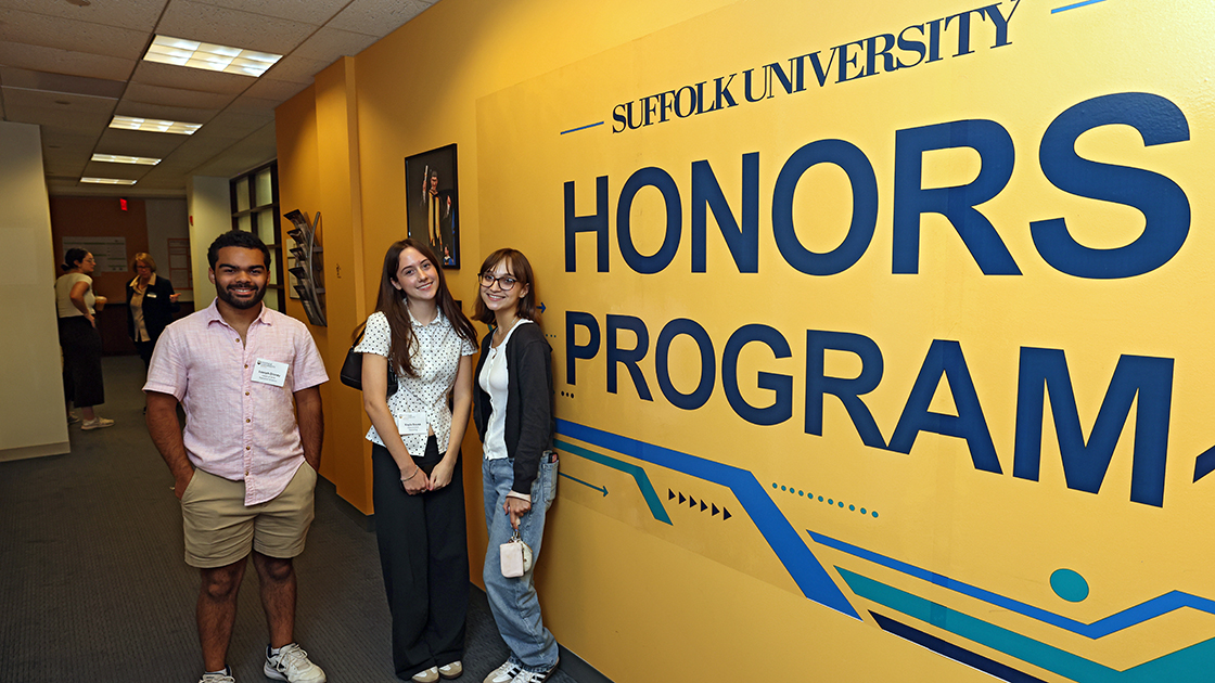 Three Suffolk University Honors students stand in front of a mural on campus.