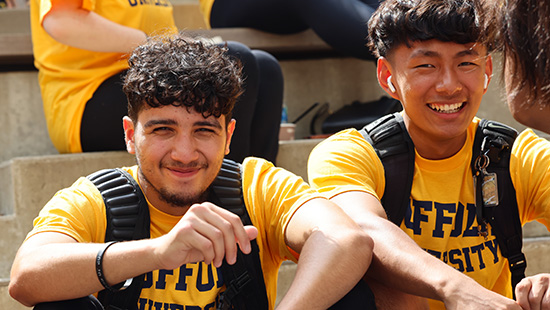 Two first-year Suffolk students outdoors at Convocation 2023.