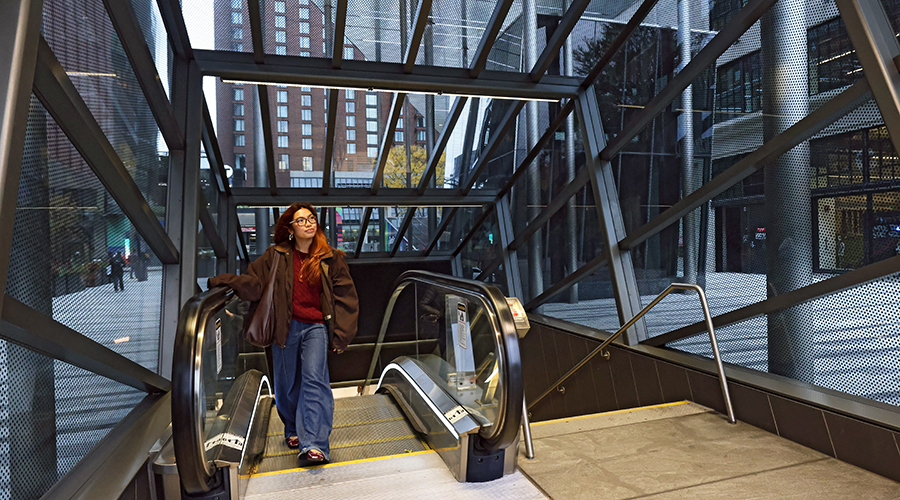 A Suffolk student exits an escalator in a train station near campus.