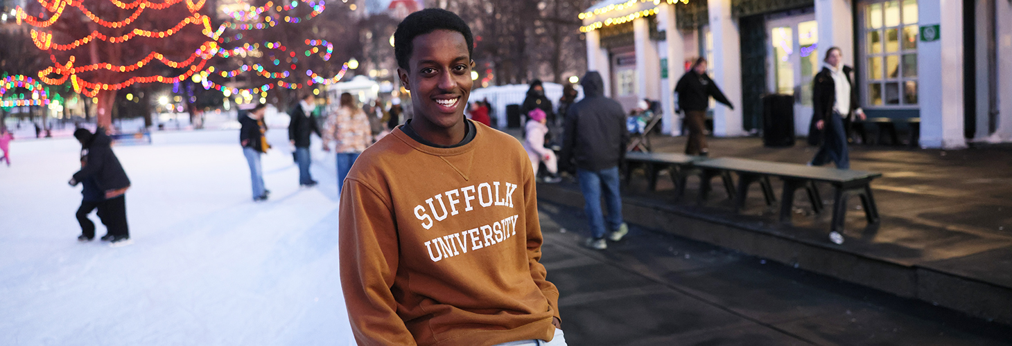 A Suffolk student leans against the edge of the ice skating rink on the Boston Common's Frog Pond.