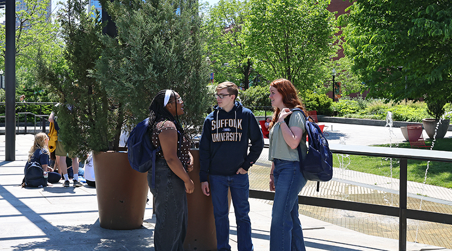 Three Suffolk students stand together with backpacks over their shoulders in downtown Boston.