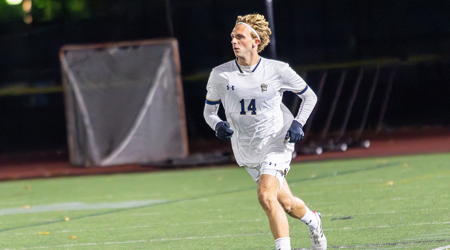 Ryan Chamberlain heads up the Suffolk soccer pitch, playing in a night game for the Suffolk men's soccer team